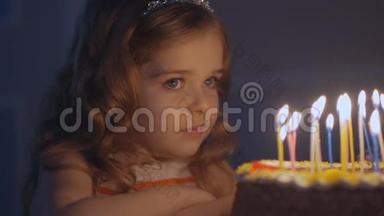 一个小女孩看着节日蛋糕上的蜡烛，慢慢地许愿