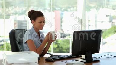 女商人在办公桌前喝咖啡