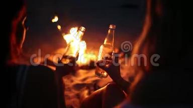 日落海滩派对，篝火晚会。 朋友们<strong>围坐</strong>在篝火旁，喝着啤酒，对着吉他唱歌。 青年