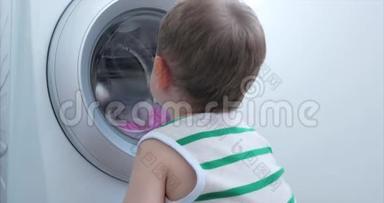 可爱的孩子在洗衣机里看。 气缸旋转机。 概念洗衣机，工业
