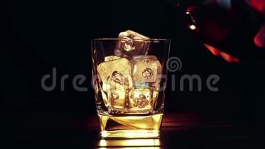 酒吧老板把威士忌倒在杯子里，木桌上放<strong>冰块</strong>，黑黑的背景，重点放在<strong>冰块</strong>上，威士忌放松时间