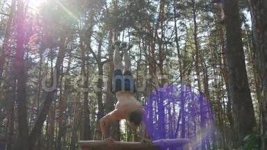 强壮的肌肉男在森林里做<strong>倒立</strong>。 肌肉男健身男在木头上做特技。 运动员