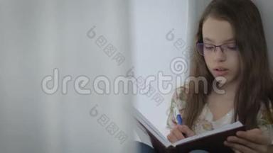 戴眼镜的严肃的小女孩勤奋地在窗口做作业。
