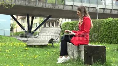 穿红裙子的女孩拿着笔记本电脑在街上工作