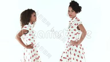 两个时装模特在工作室摆姿势。 美国黑人模特和亚洲模特在白色背景下分离。 时尚镜头。