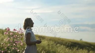 肖像快乐的年轻女子在一个夏天散步在田野近距离。 年轻漂亮的女人在夏天的田野里散步。 微笑