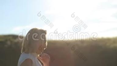 肖像快乐的年轻女子在一个夏天散步在田野近距离。 年轻漂亮的女人在夏天的田野里散步。 微笑