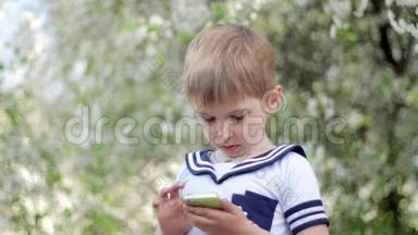小男孩在智能手机上玩游戏。 春天公园