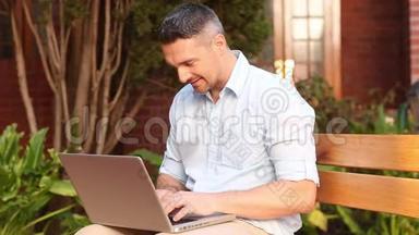 快乐的讲师坐在长凳上用笔记本电脑