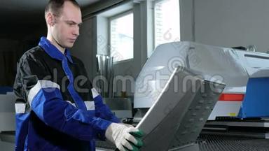 机械技师编程<strong>冲床数控</strong>。 一名男子仔细输入数据以控制面板。 金属