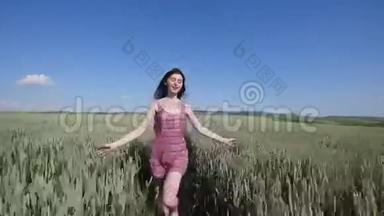在绿色的麦田上奔跑的美女。自由概念。快乐的女人在户外。收获