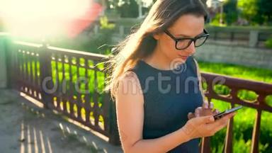 日落时分，女人在街上散步时使用智能手机
