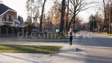 运动的女人在公园的混凝土<strong>跑道上</strong>缓慢地跑着。 健康健身理念