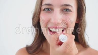 微笑的女人用唇膏抹唇