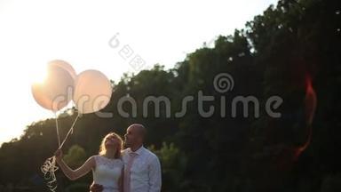 结婚那天的<strong>浪漫</strong>情侣。 新娘和新郎带着气球在<strong>夕阳</strong>的田野里。
