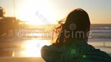 在海滩上拿冲浪板的年轻女孩。站在海边冲浪的女人。美丽的日落，风在<strong>吹拂</strong>