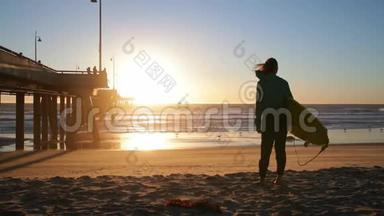 在海滩上拿冲浪板的年轻女孩。站在海边冲浪的女人。美丽的日落，风在吹拂