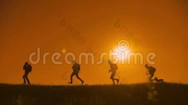 人们徒步旅行的人群幸福地奔跑着，四个人在夕阳的上方遛达着游客阳光下的狗影