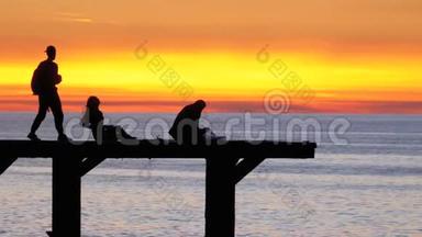 日落时海上码头上的人剪影