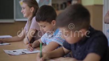 老师在课堂上帮助学校的孩子写作测试。 教育、小学、学习和人的概念