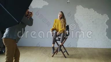 年轻漂亮的女模特在室内照相馆用数码相机拍照时为摄影师摆姿势