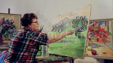 一个女人用调色板和画笔用油画颜料描绘风景。