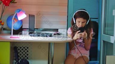 小女孩在智能手机上耳机听音乐。 青少年女孩在社交中翻阅播放列表音乐
