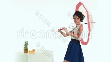 亚洲女人带着一把带有圆点图案的伞在工作室里摆姿势。 菠萝a