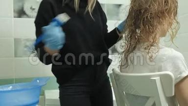 女理发师在家里的浴室里给一个年轻女人的头发涂上油漆，用刷子涂上油漆