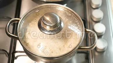 烹饪盘上的锅。 大麦粥在锅里煮熟。 平底锅里的水沸腾了，冒泡了。