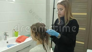 女理发师在家里的浴室里给一个年轻女人的头发涂上<strong>油漆</strong>，用<strong>刷子</strong>涂上<strong>油漆</strong>