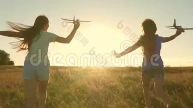 快乐的童年概念。 飞行的<strong>梦想</strong>。 两个女孩在日落时玩玩具飞机。 以太阳为背景的<strong>儿童</strong>