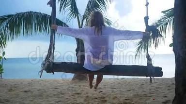 一个女孩在海滩上的绳索秋千上摇摆