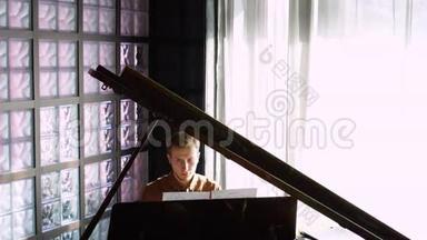 弹钢琴。 那个年轻人弹钢琴。 这位美丽的钢琴家演奏旋律。 室内窗户发出<strong>悦耳</strong>的灯光