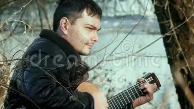 在河边弹吉他的年轻人