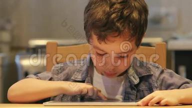 <strong>端</strong>口：一个可爱的孩子使用平板<strong>电脑</strong>在家里的一张桌子。 休闲服装