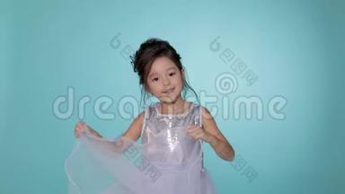 漂亮的<strong>小女孩</strong>穿着银色的裙子在蓝色的背景上<strong>跳舞</strong>。