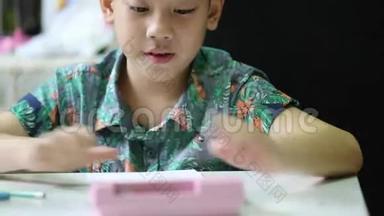 亚洲可爱的男孩独自在家做作业。