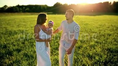 家庭幸福。 <strong>爸爸妈妈</strong>和一个小女孩，在夕阳下穿着白色衣服的田野里散步