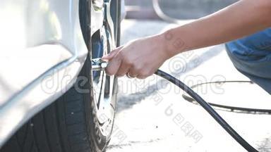 女人检查压力和充气汽<strong>车轮胎</strong>。