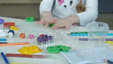 一个小女孩玩橡皮泥，滚球，桌面上有图形和彩色铅笔，发展