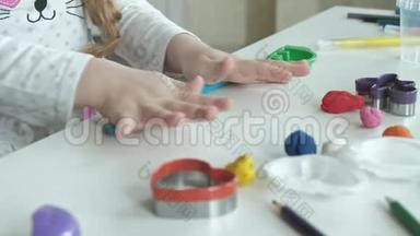 一个小女孩玩橡皮泥，滚球，<strong>桌面上</strong>有图形和彩色铅笔，发展