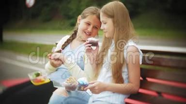 两个小女孩，苗条又胖，吃健康有害的食物，蔬菜和蛋糕坐在咖啡馆的长凳上，