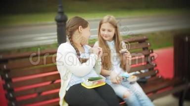 两个小女孩，苗条又胖，吃<strong>健康有害</strong>的食物，蔬菜和蛋糕坐在咖啡馆的长凳上，