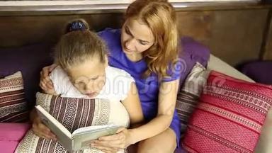 年轻的妈妈在<strong>睡前</strong>在沙发上的客厅里大声地给女儿读一本书