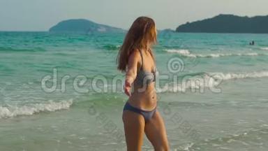 慢镜头拍摄一个年轻的暴跳如雷的女人在海滩和海里玩