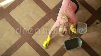 女人打扫地板。 戴手套的女孩打扫厨房