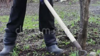 一个女人在花园里工作，用一把锄头把草从地上移走