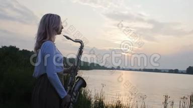 黎明时分，一位年轻女子在河岸附近的萨克斯管上演奏，一位穿着一件长带着风的美丽女孩的剪影