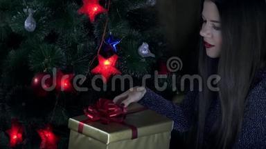 一个女孩拿着礼物，坐在圣诞树下